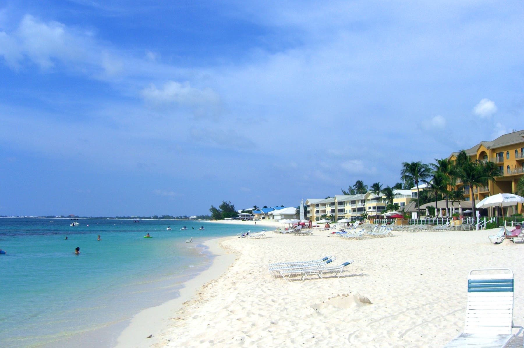 Seven Mile Beach with lounge chairs, palms, and hotels along the sand