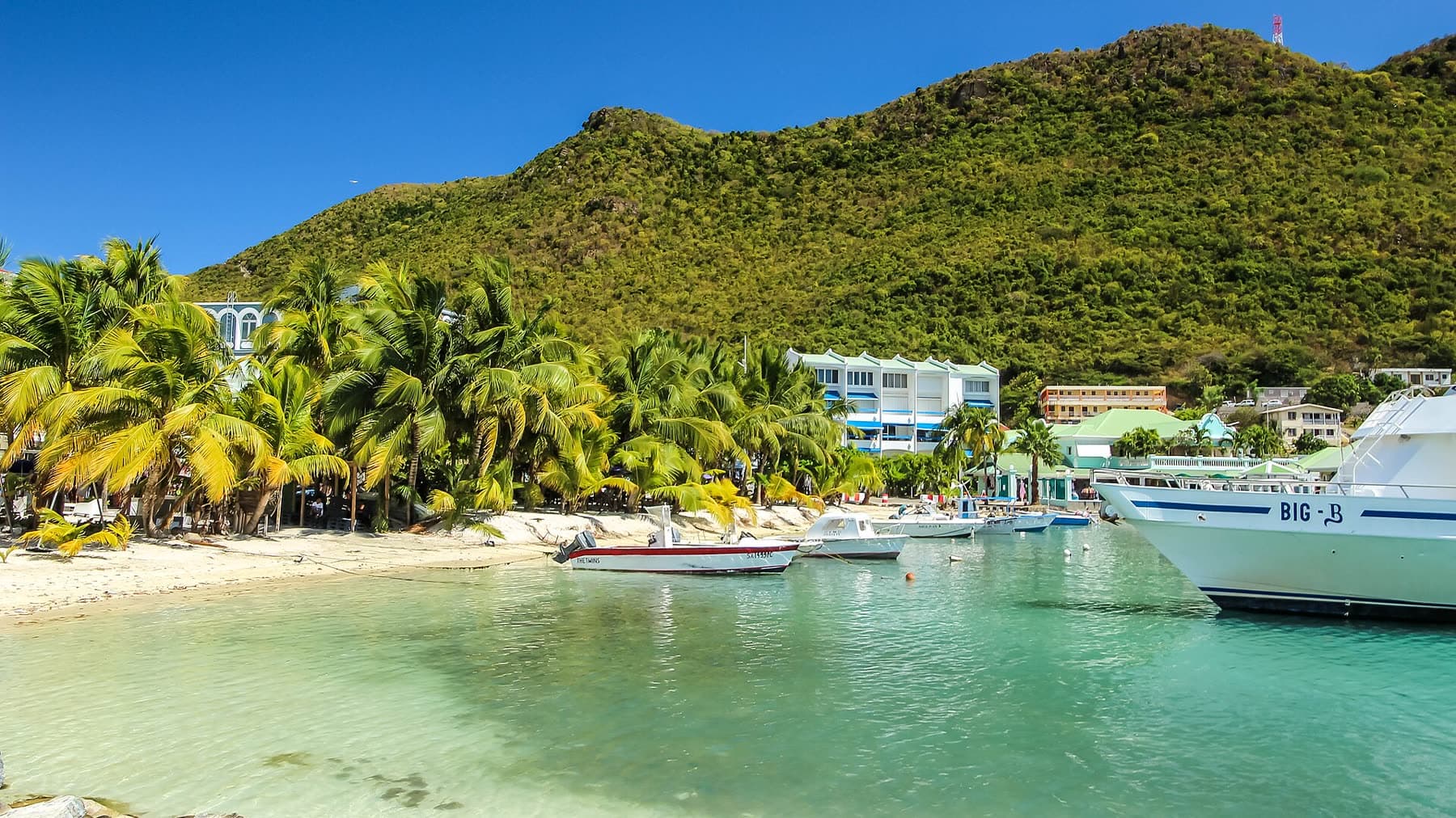 Philipsburg waterfront on Great Bay, with turquoise water, palms, boats, and town buildings
